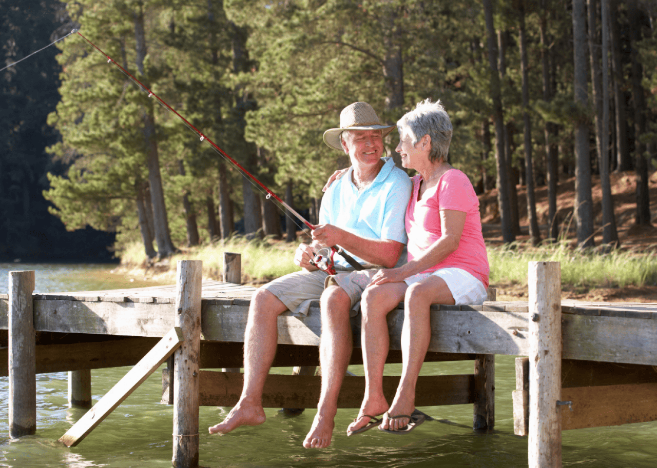 Senior couple sitting on a lakeside dock and fishing