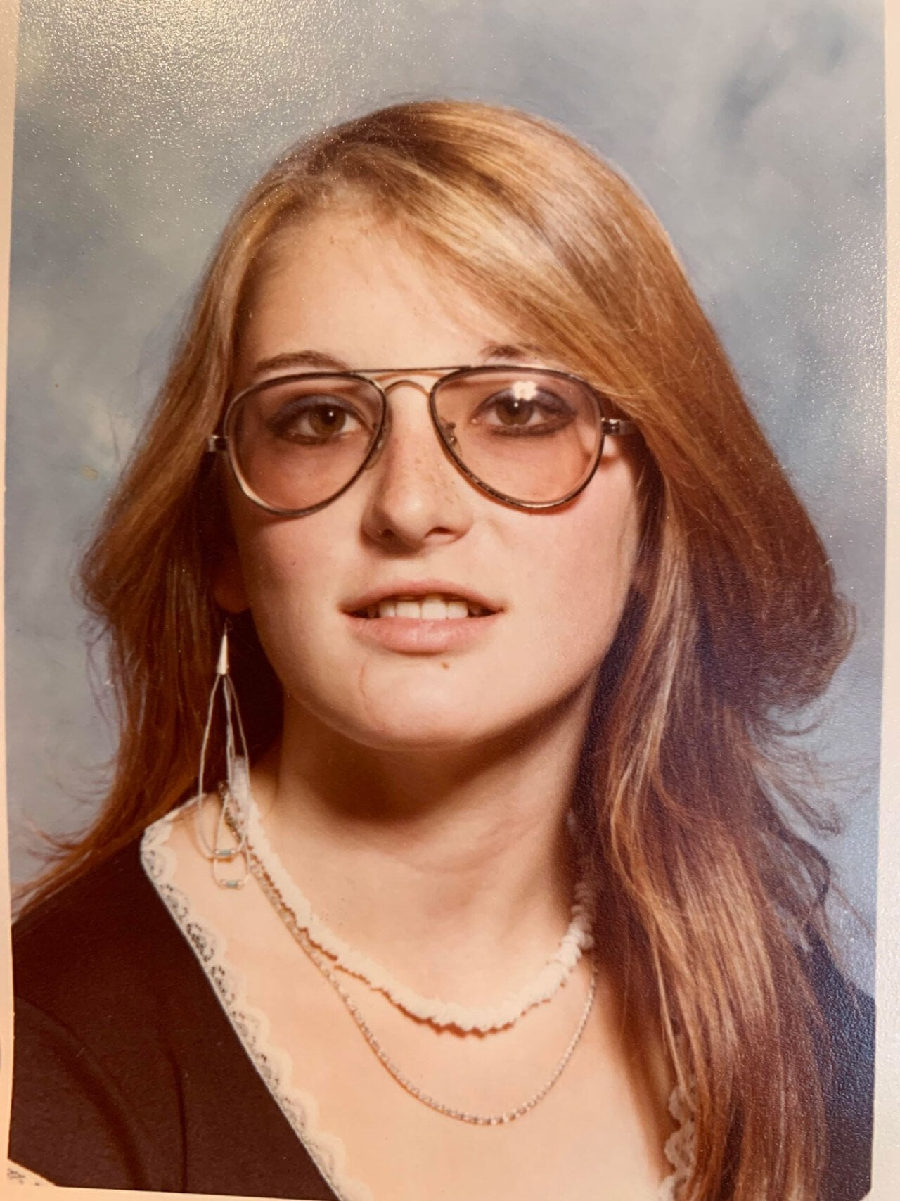 A school photo of a girl in high school wearing cool glasses