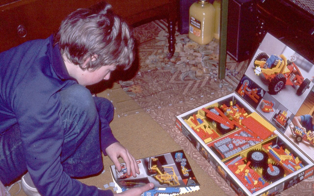 Kid leaning over Legos and a Lego instruction manual