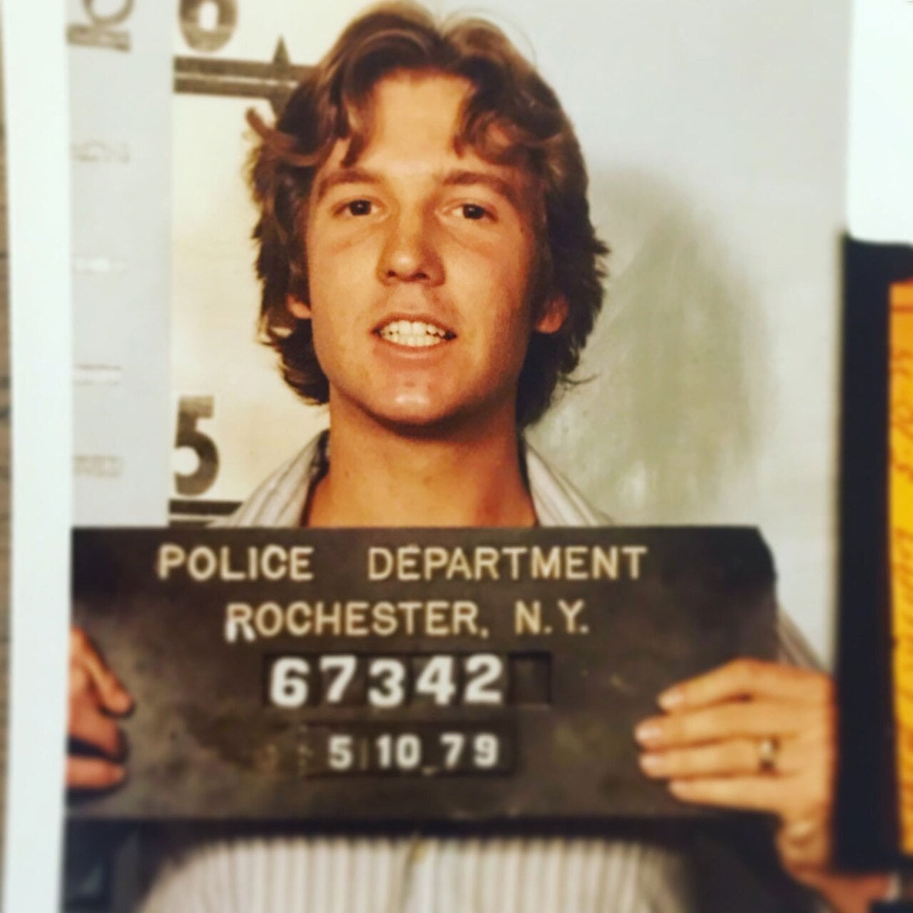 A young man holding up a sign for his mugshot