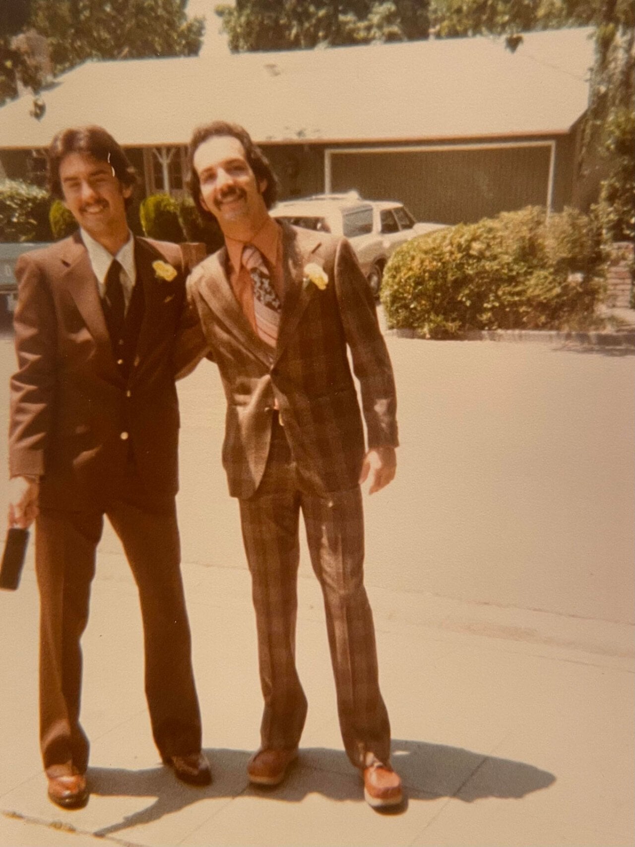 Two young men in suits with corsages
