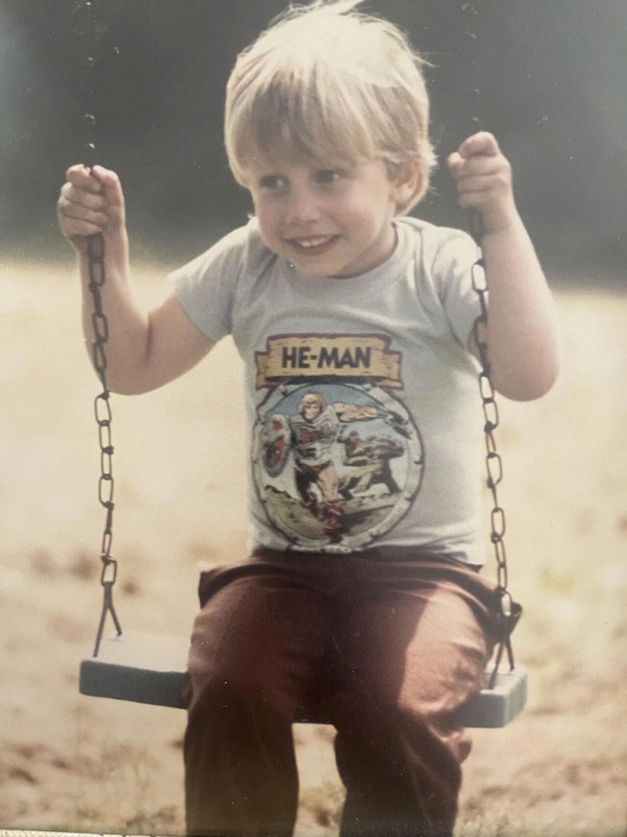 Little boy wearing a He-Man shirt on a swing