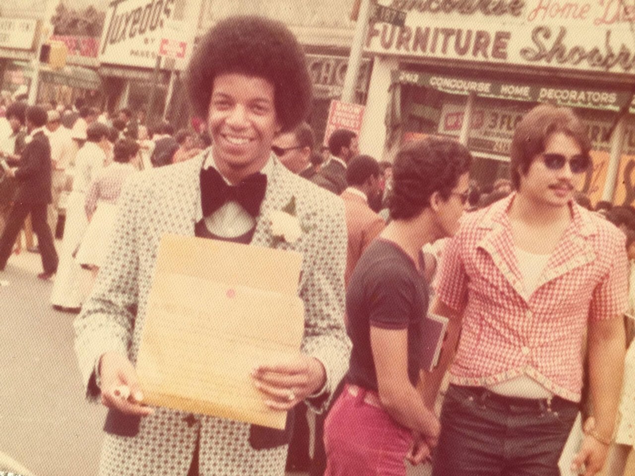 A man in a suit smiling with his diploma 