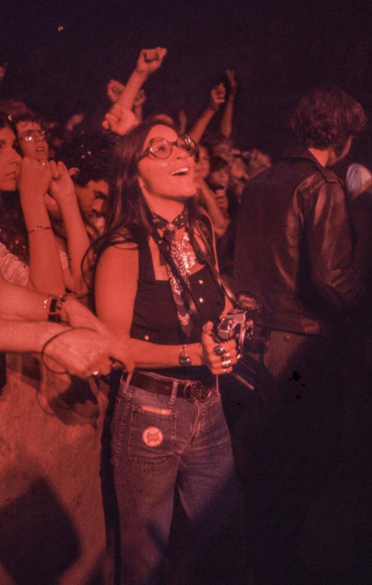 Photo of a young woman holding a camera and looking in awe up on a stage