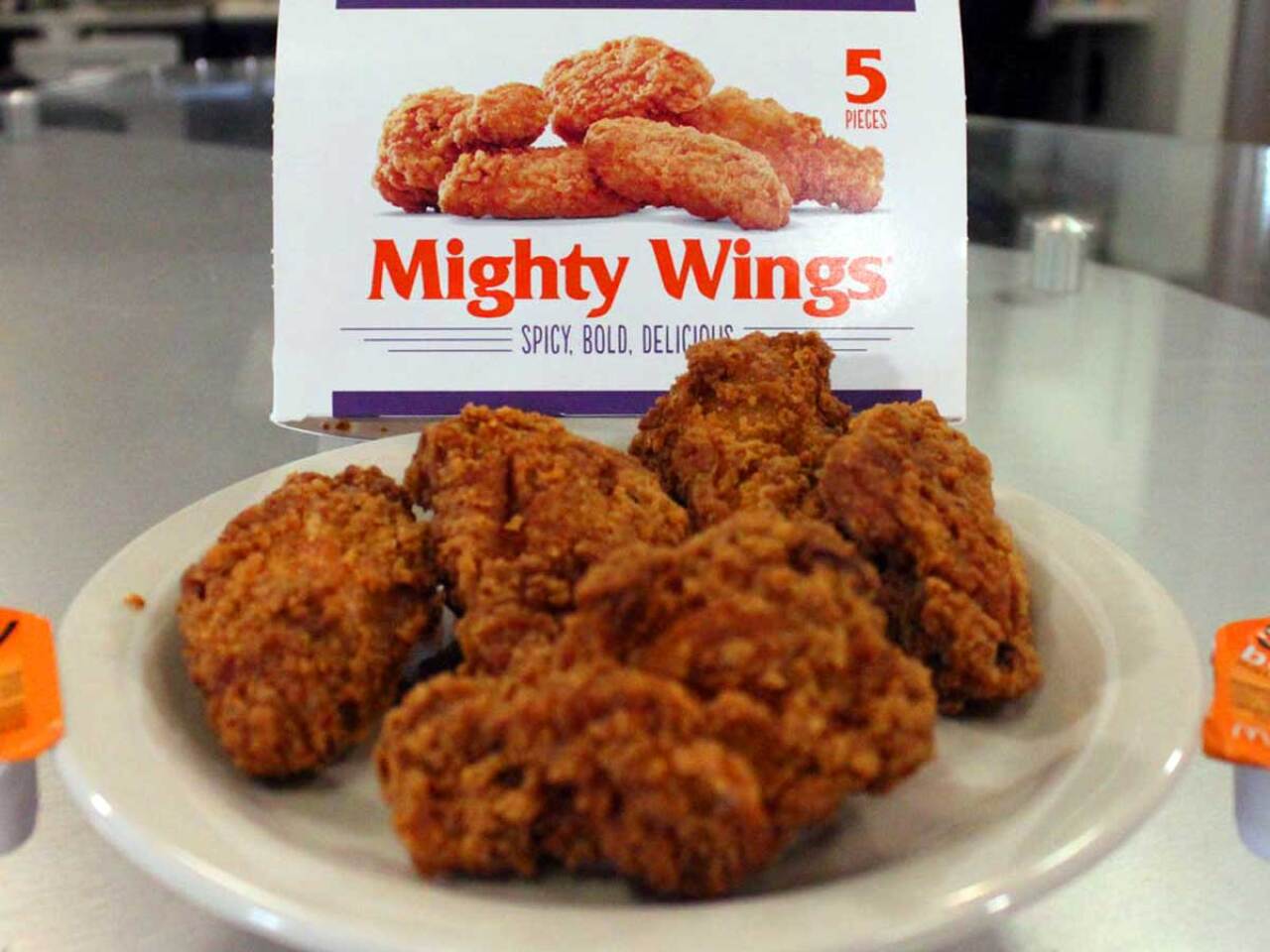 Some McDonald's Mighty Wings on a plate in front of the original packaging