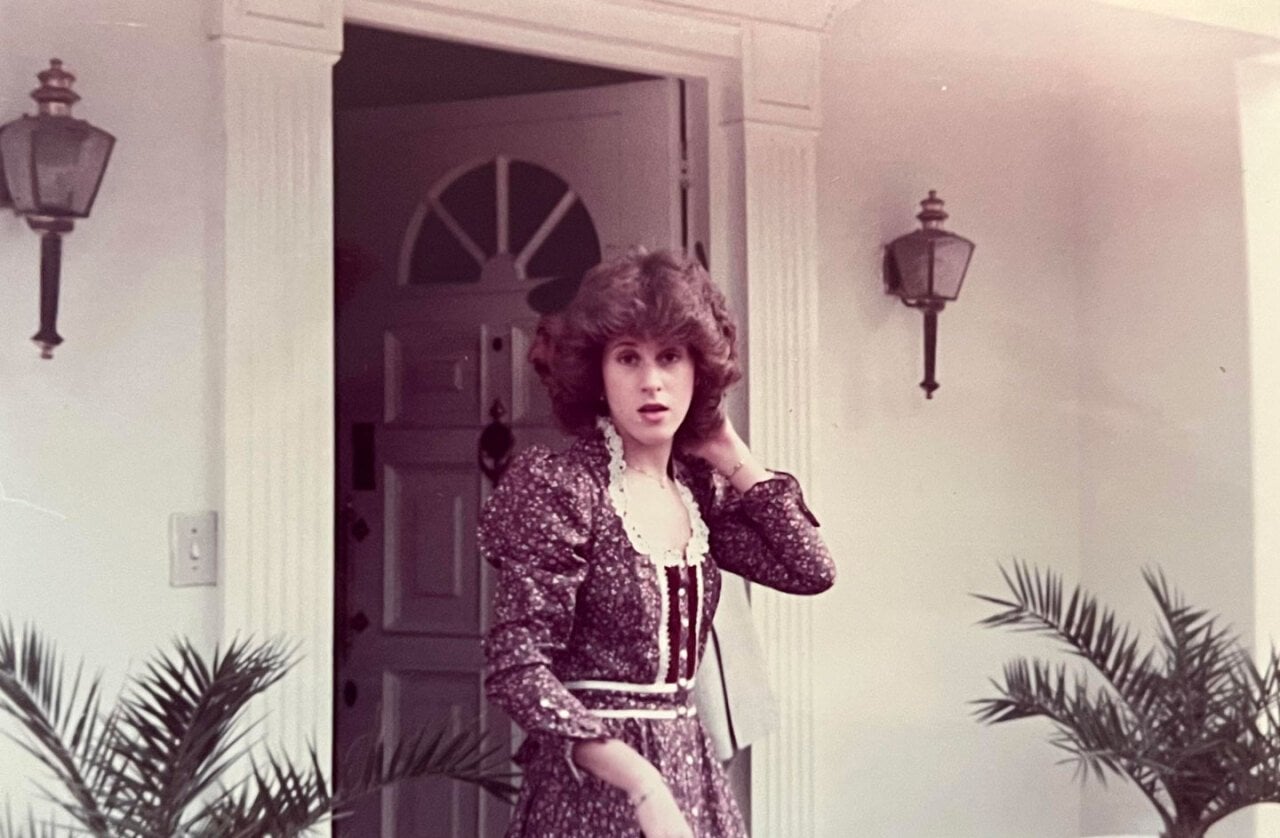 A woman wearing a very 80s dress headed out the front doorb