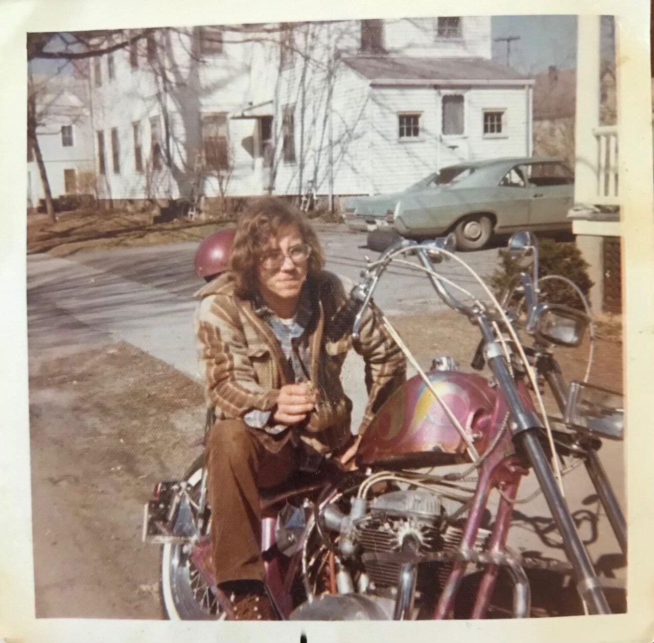 A young man sits on a pink motorcycle in a driveway