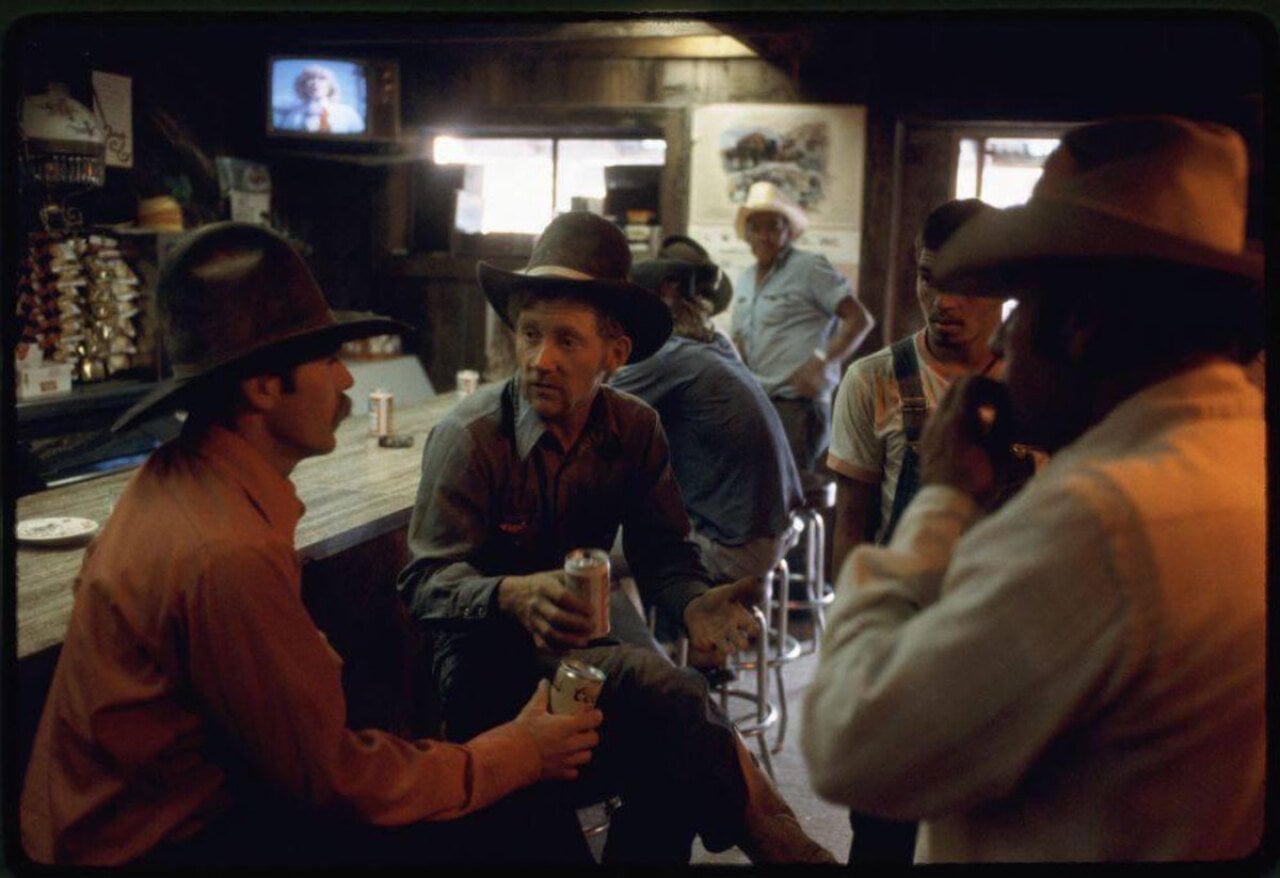 Couple of cowboys sitting around talking inside a bar