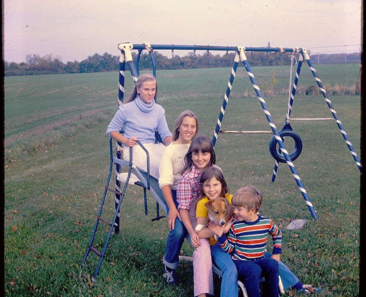 Five kids of varying ages are all posing on a slide