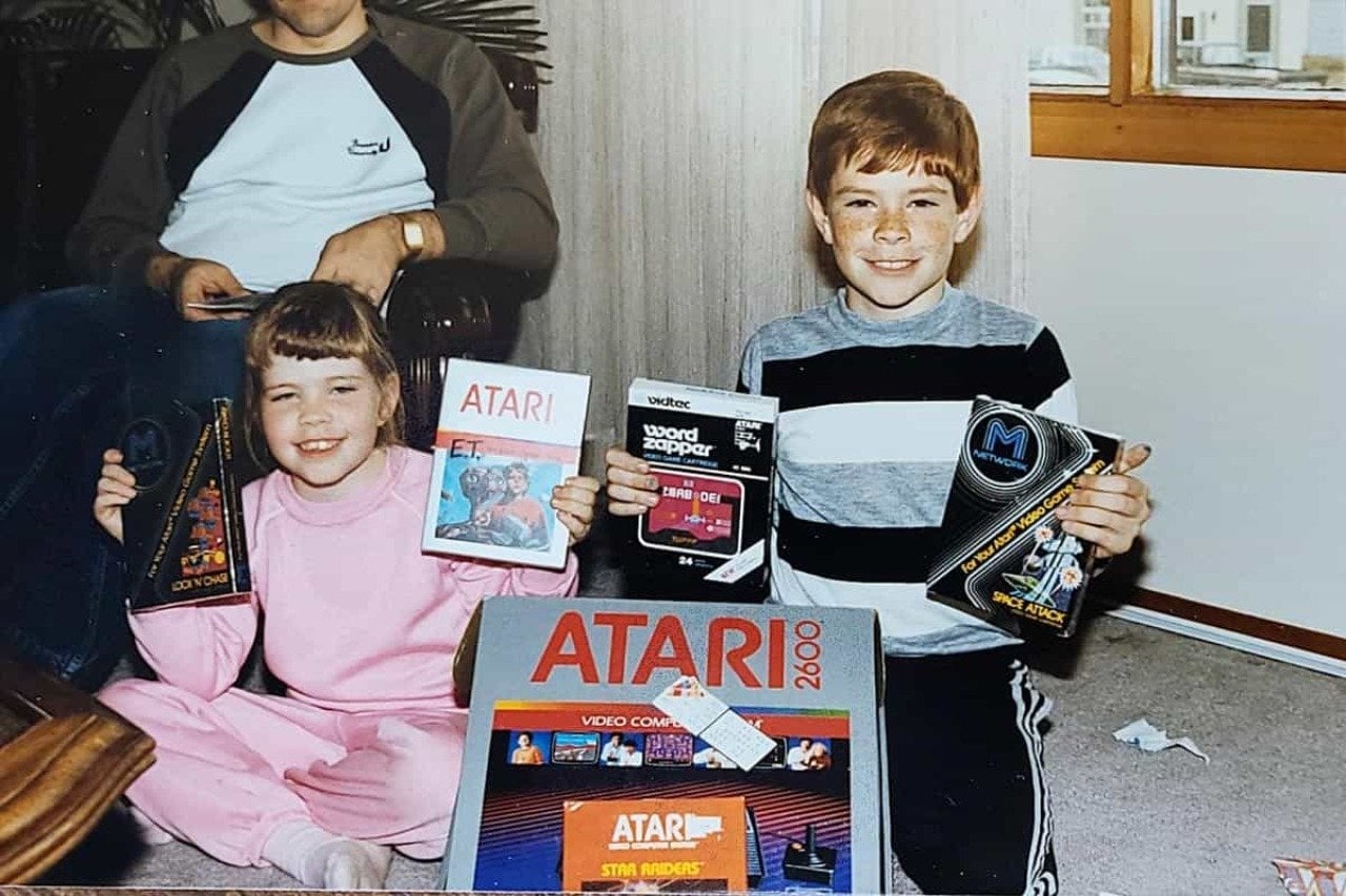 Two kids holding up their Atari games and the new Atari console