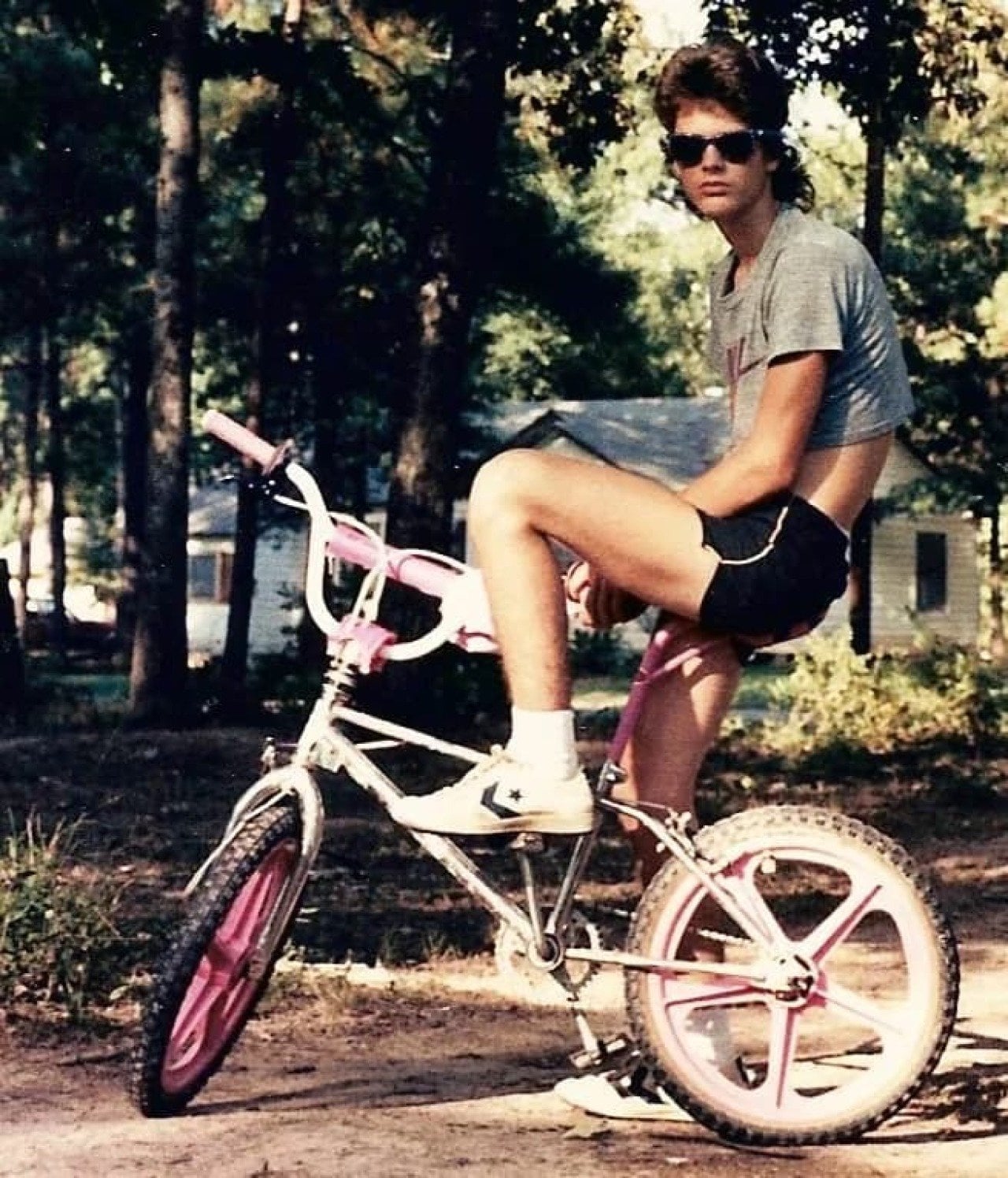 Kid with a mullet sitting on a BMX bike