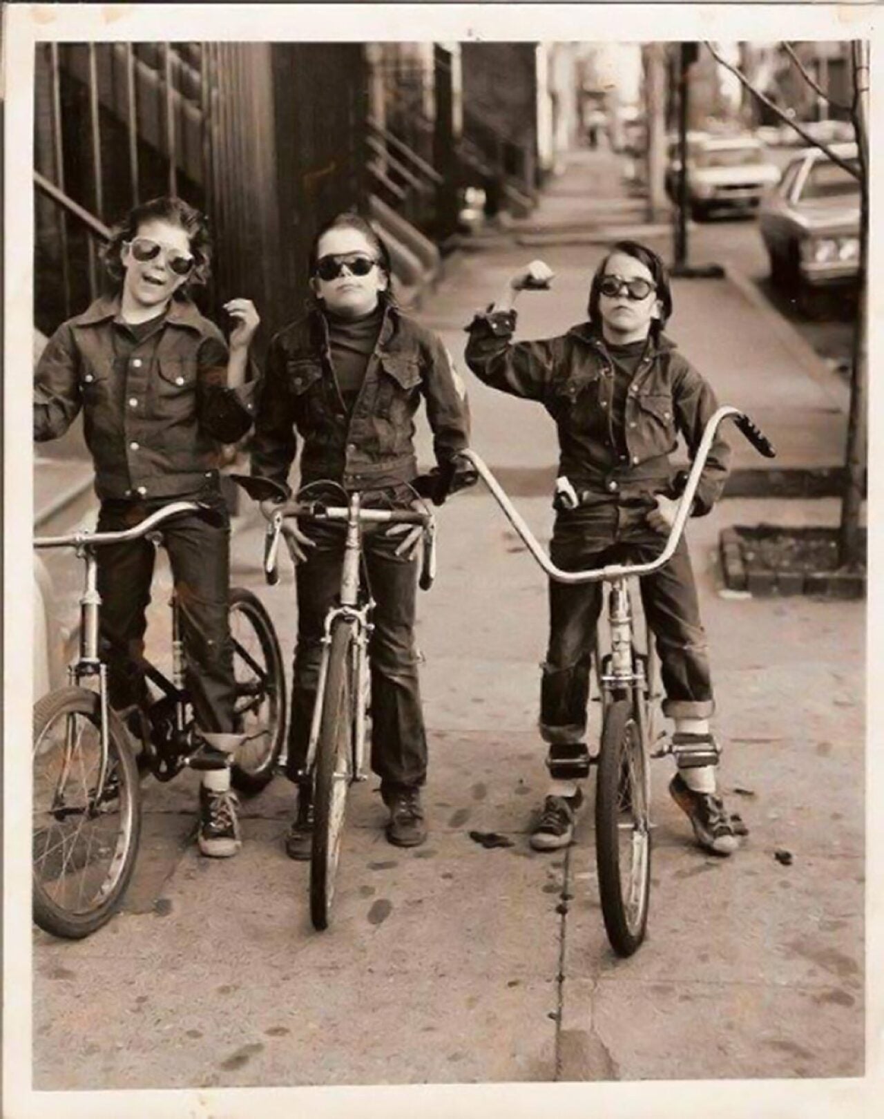 Three kids on bikes wearing sunglasses and denim jackets