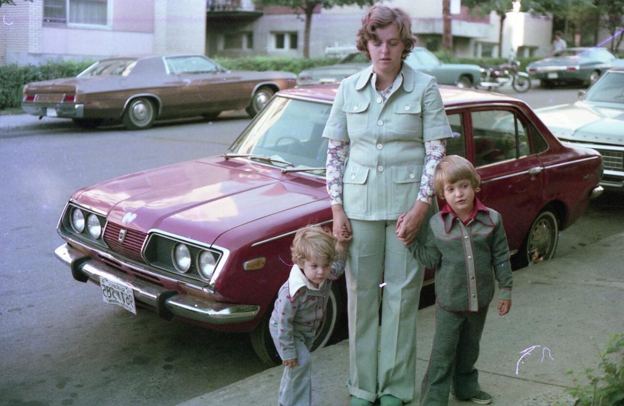 Two kids with their mother on the sidewalk dressed in very 1970s clothes