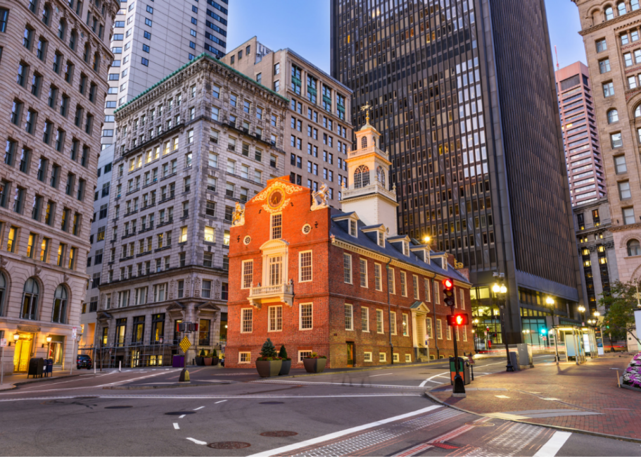 A city street with skyscrapers and an old red brick building at dusk. 