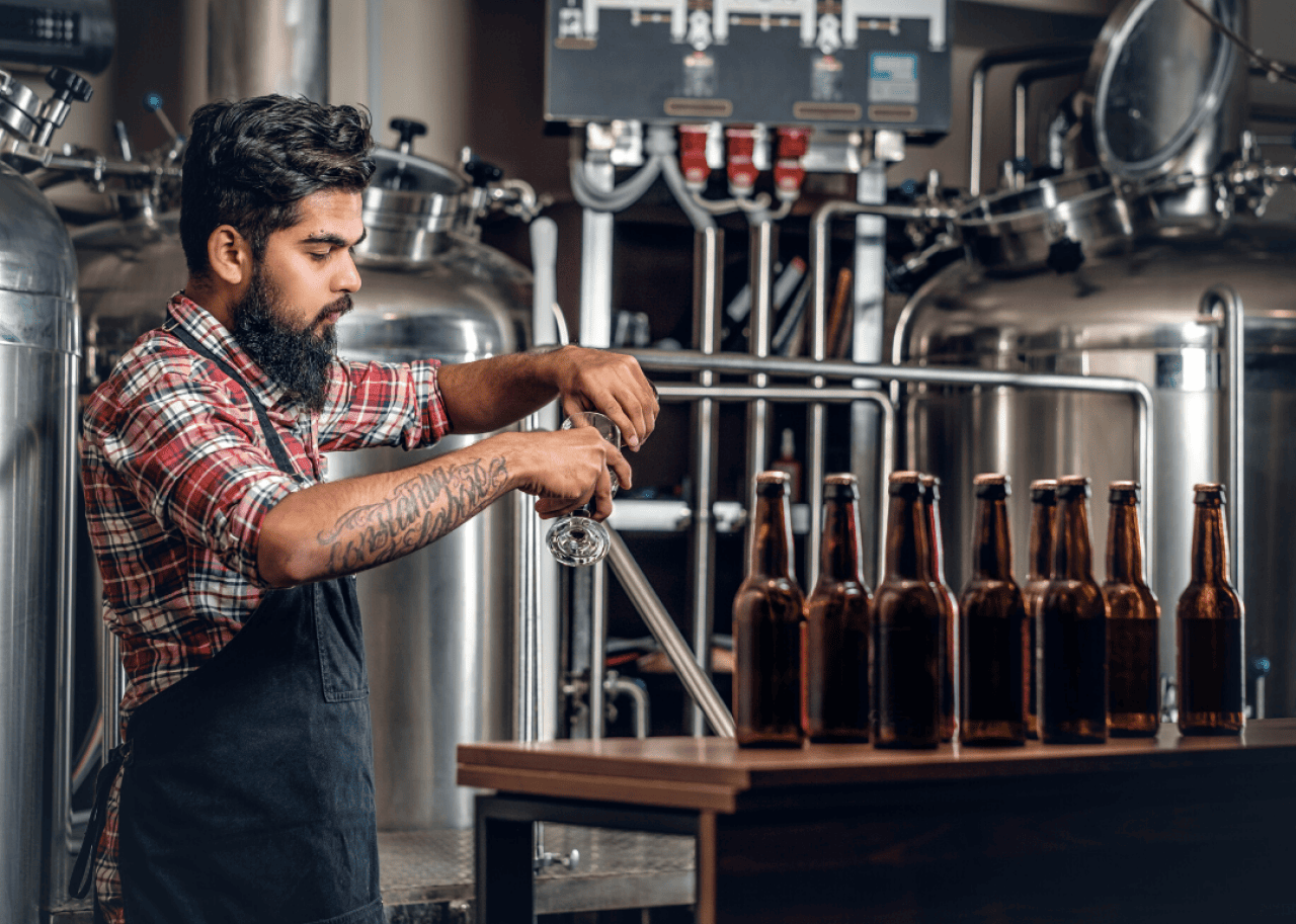 A brewer samples a batch of beer.