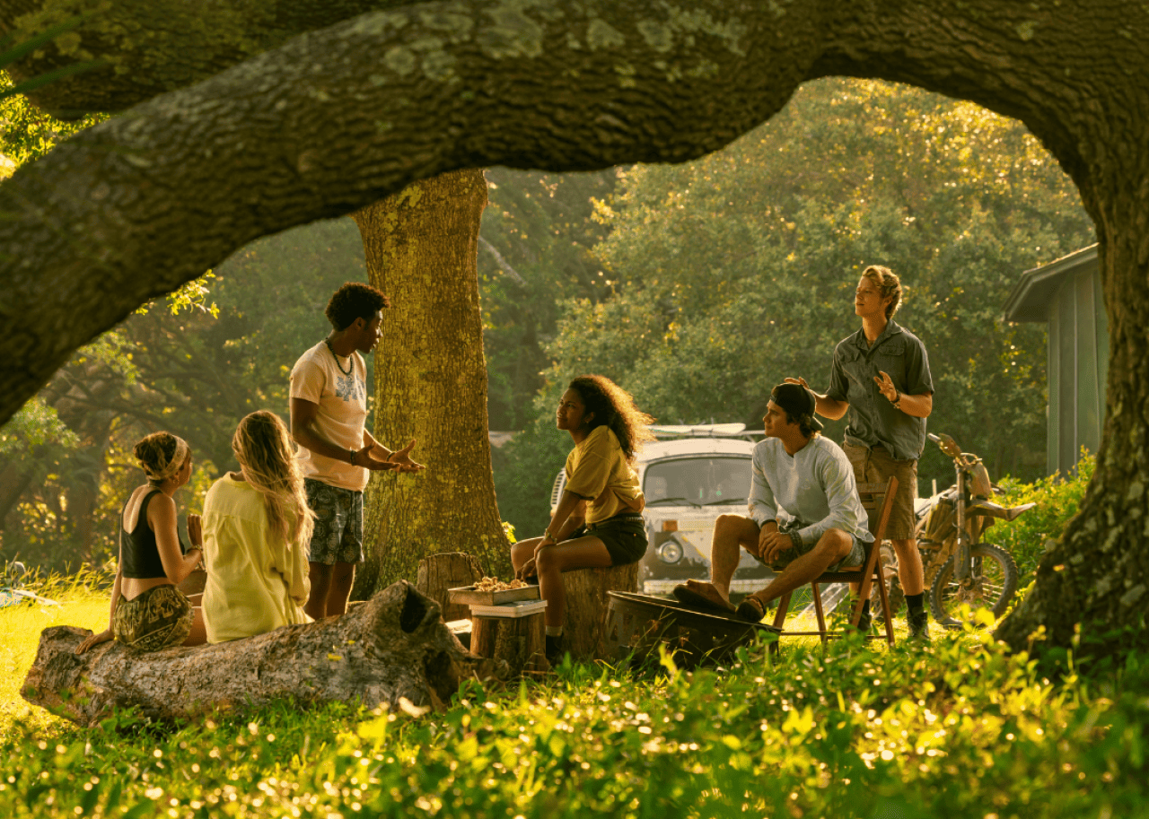 A group of young people talking under a tree.