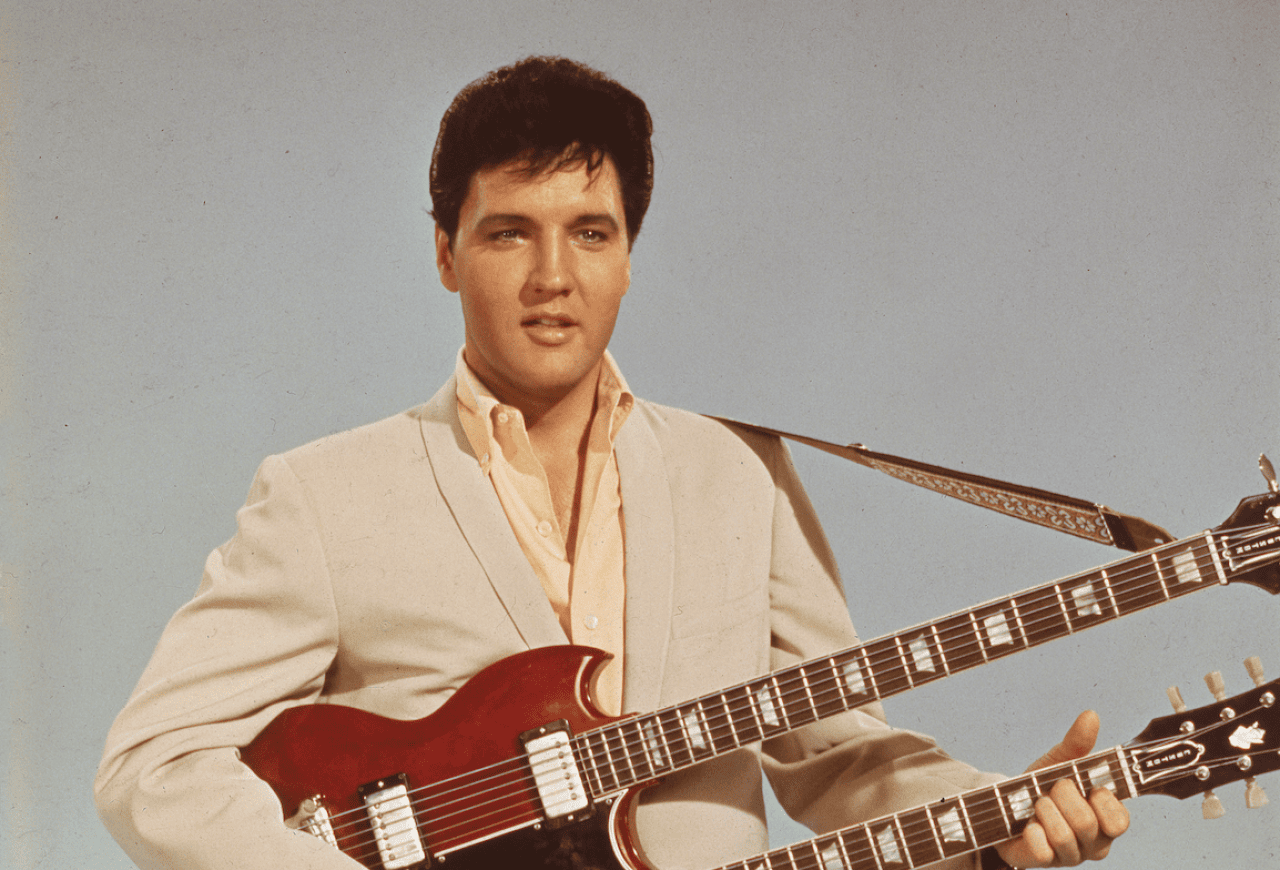 Elvis in a publicitiy still holding a guitar