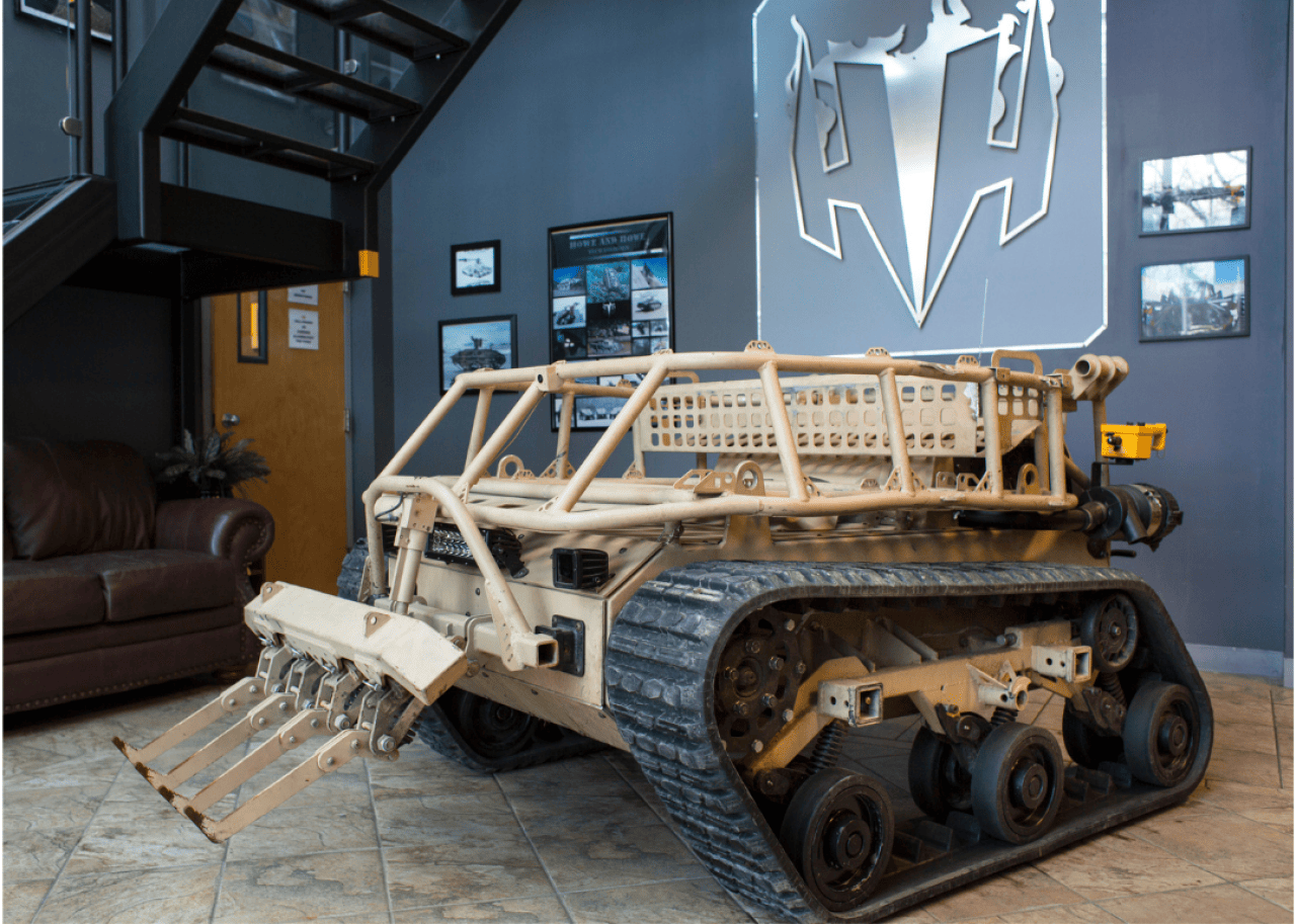 A relatively small military tank robot on display in a building.