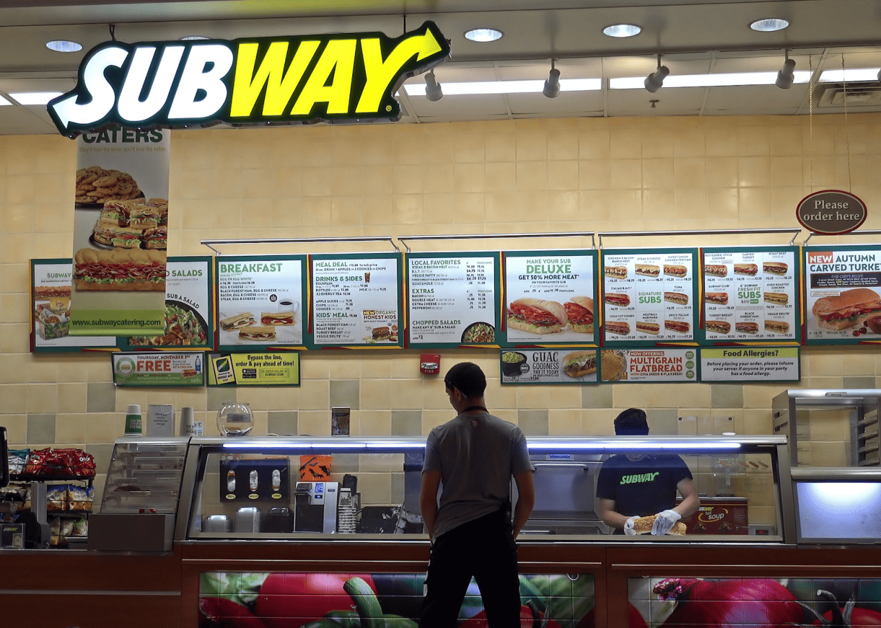 Someone ordering a sandwich at a Subway.