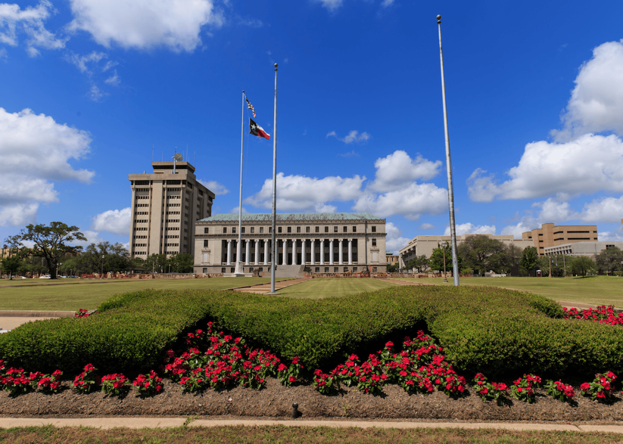 A large rectangular building with columns in the front and a green lawn.