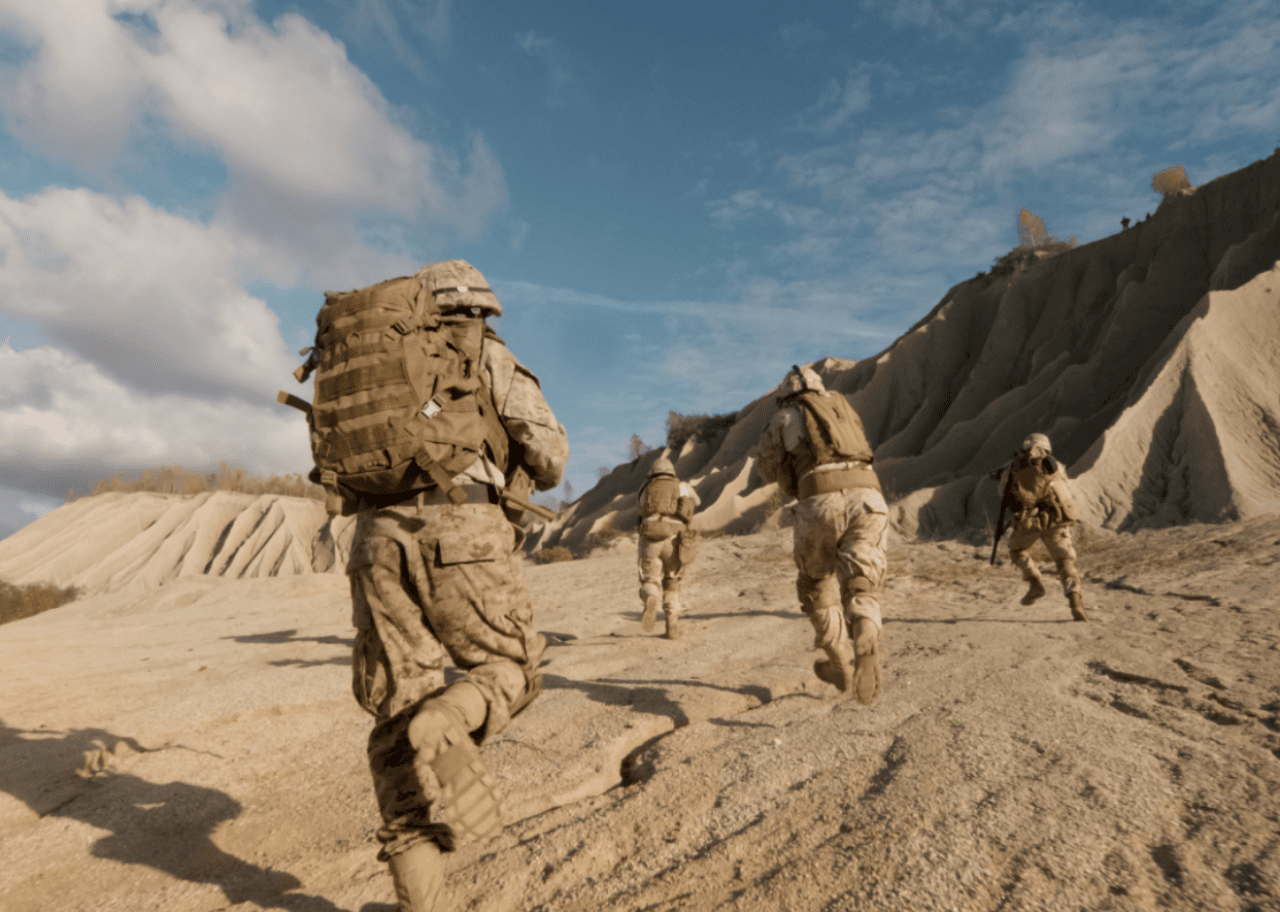 Soldiers in camo running in a desert landscape.