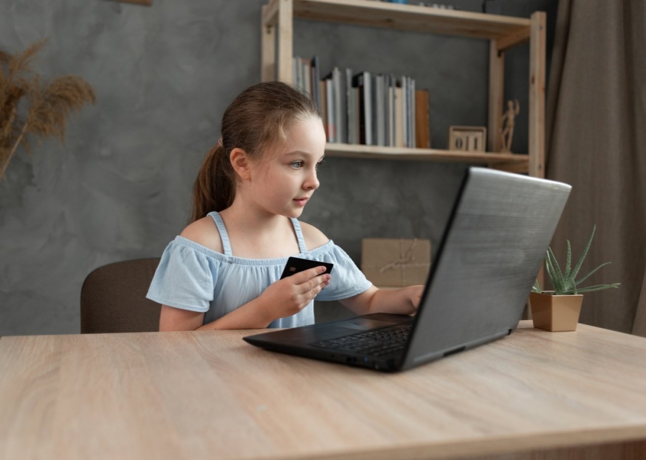 Happy girl makes a credit card purchase on a laptop.