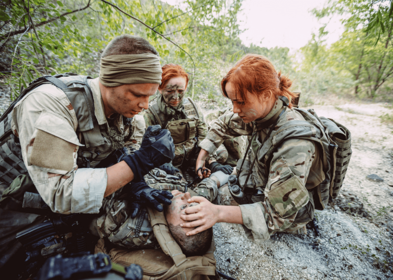 Soldiers in the field checking on an injured person.
