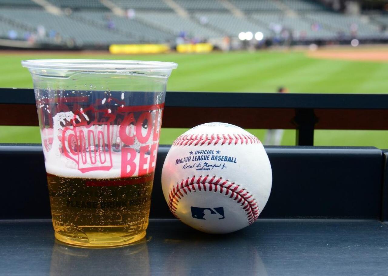 A cup of beer and a baseball at a Major League ballpark.