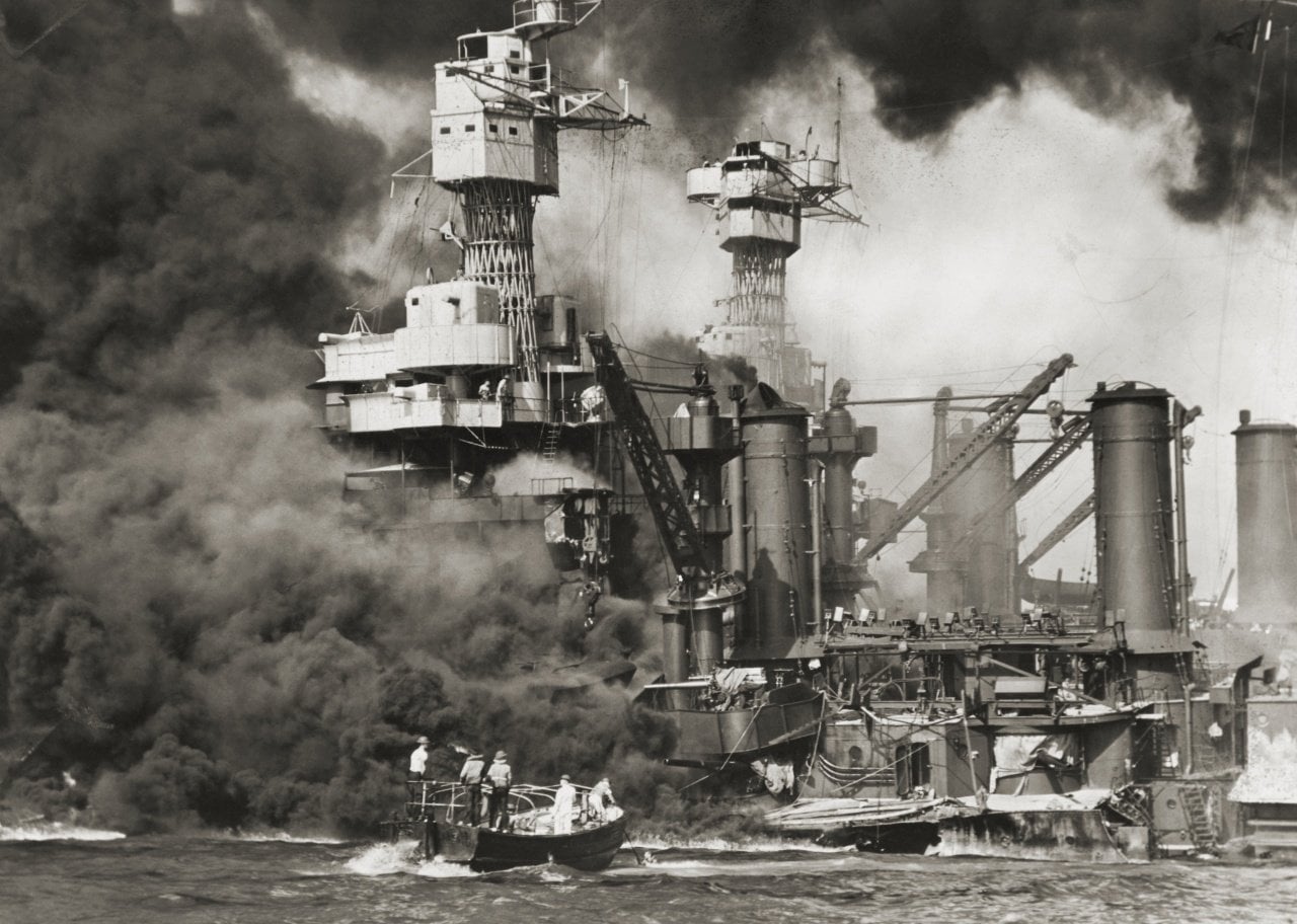 Rescue boats heading to naval ships on fire in Pearl Harbor.