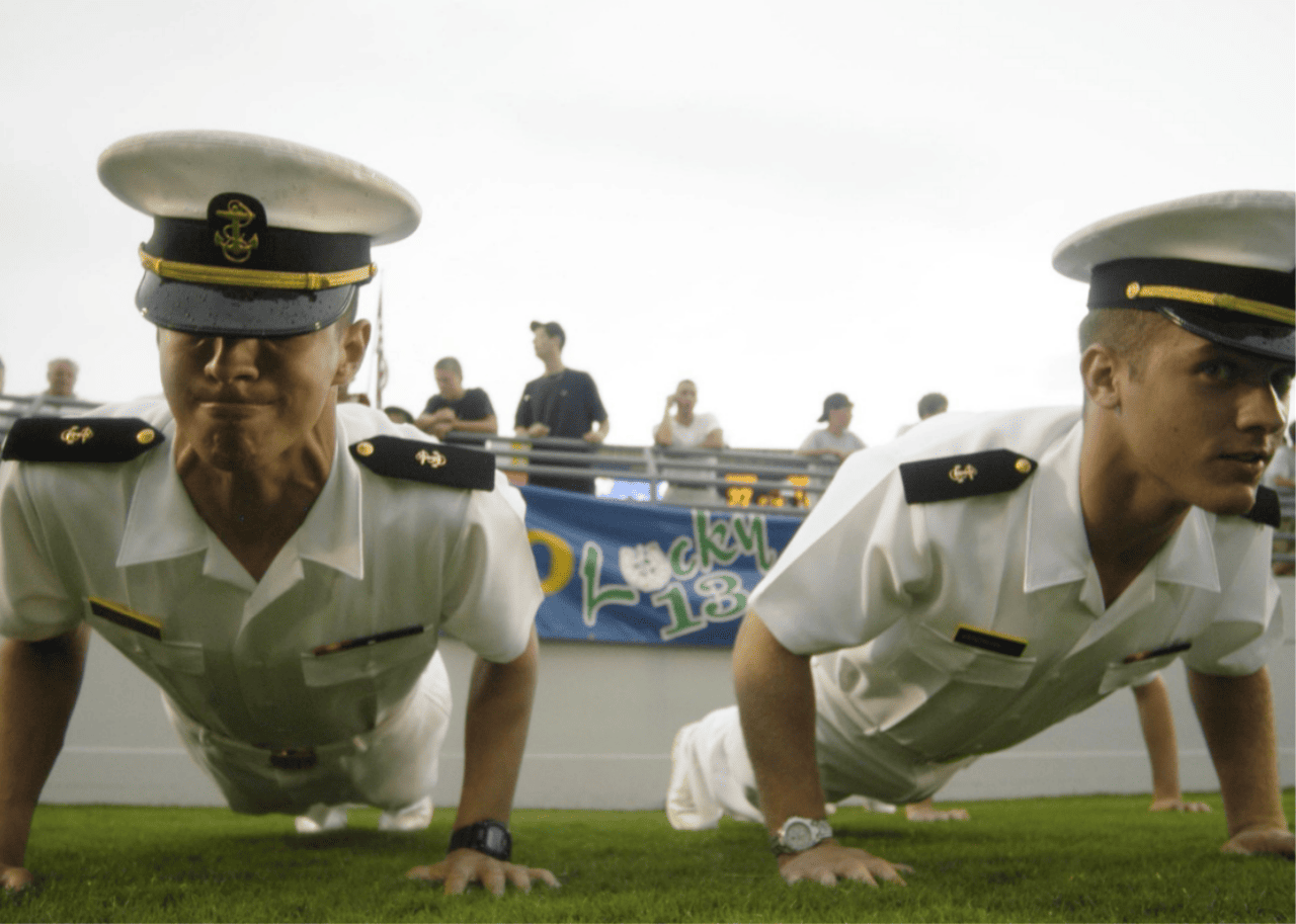 Naval sailors in uniform doing push ups.