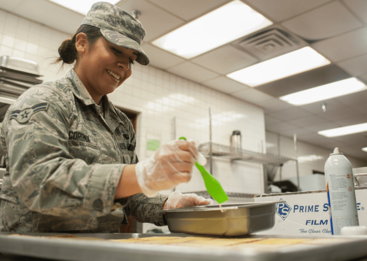 A woman in camo preparing food.