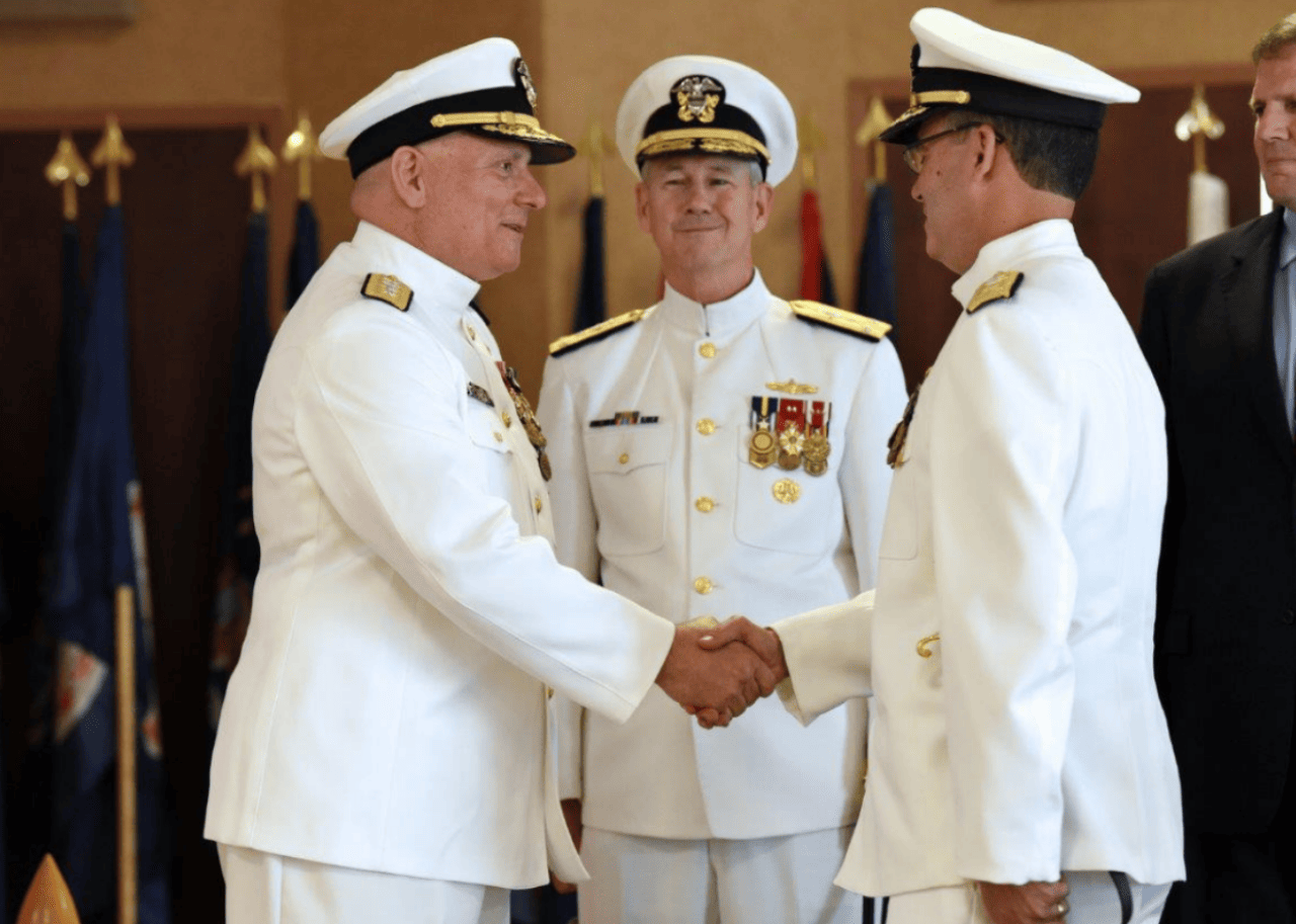 Naval officers in white uniforms shaking hands.