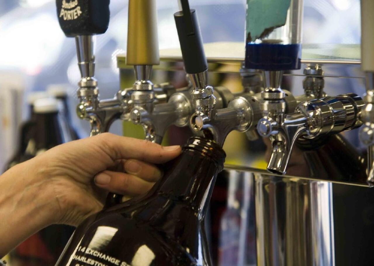 A growler of beer being filled at a pub.