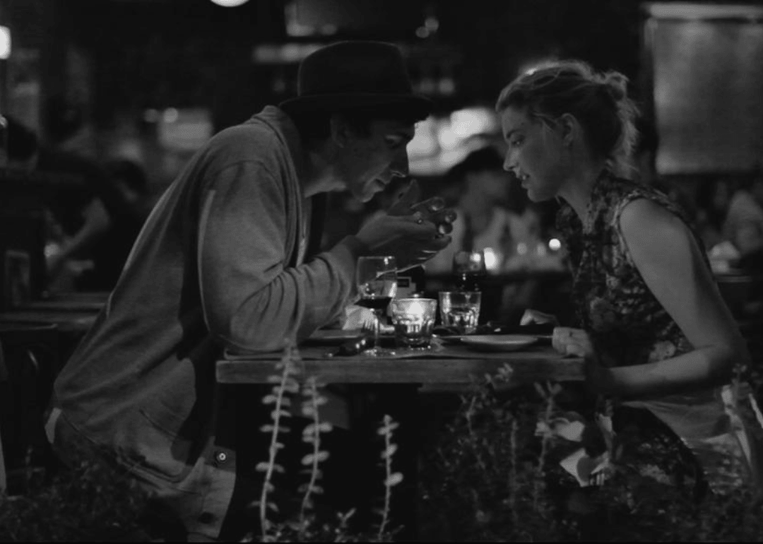 A man and woman sit at a restaurant table together looking at something.