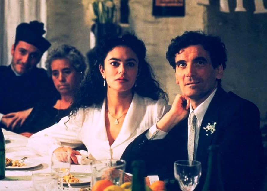 A man and woman sit together at a dinner table looking up at something.