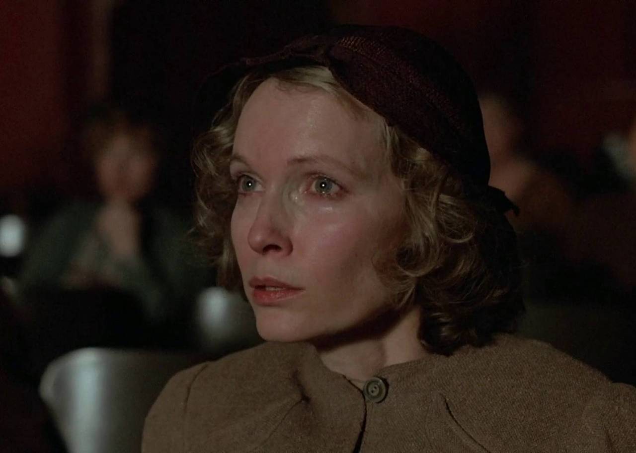 A woman sits in a theater crying.