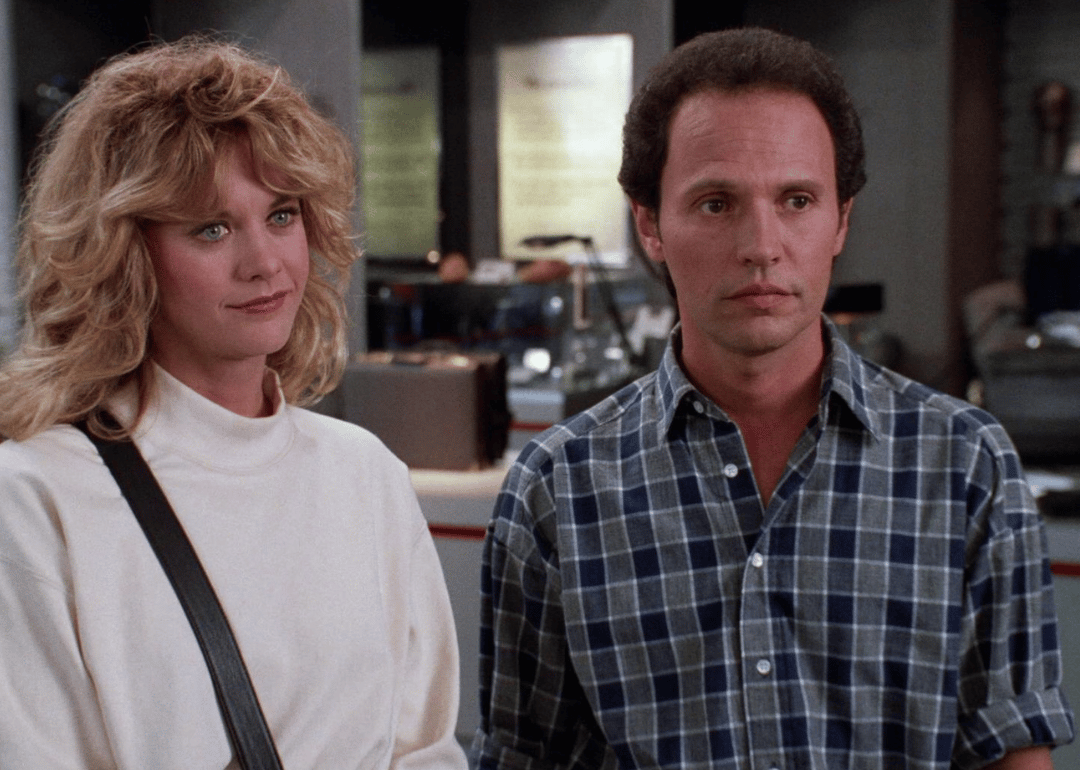 A man and a woman stand next to one another looking at someone else.