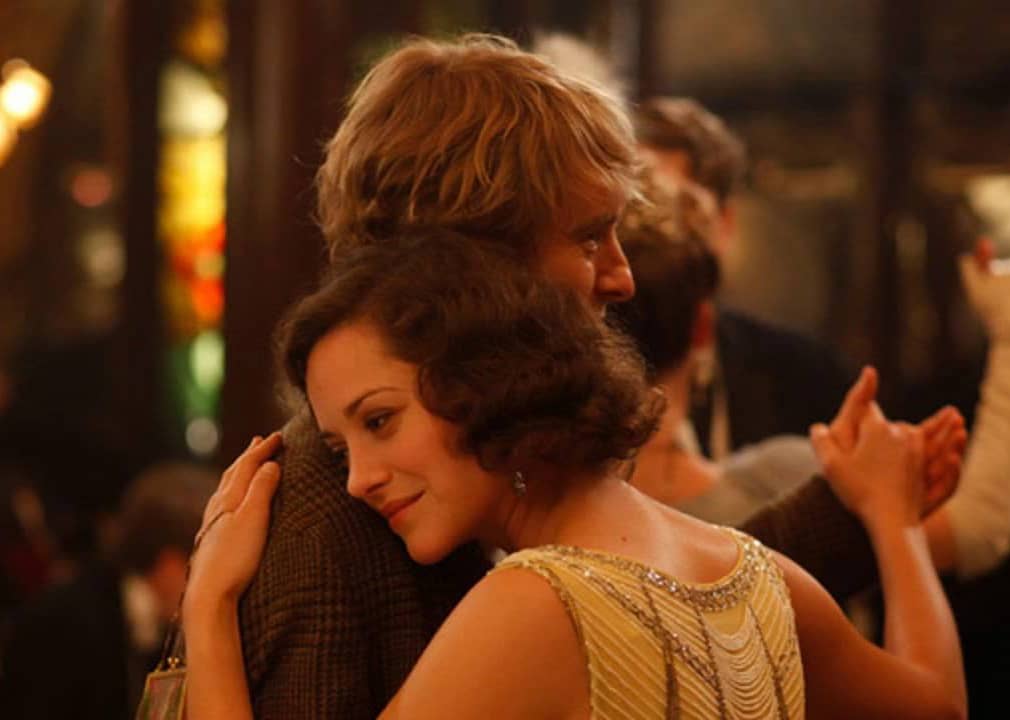 A blonde haired man dances with a woman in a flapper dress.
