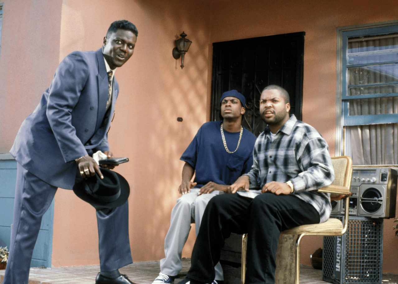 Chris Tucker, Ice Cube, and Bernie Mac in front of a house in a scene in Friday.