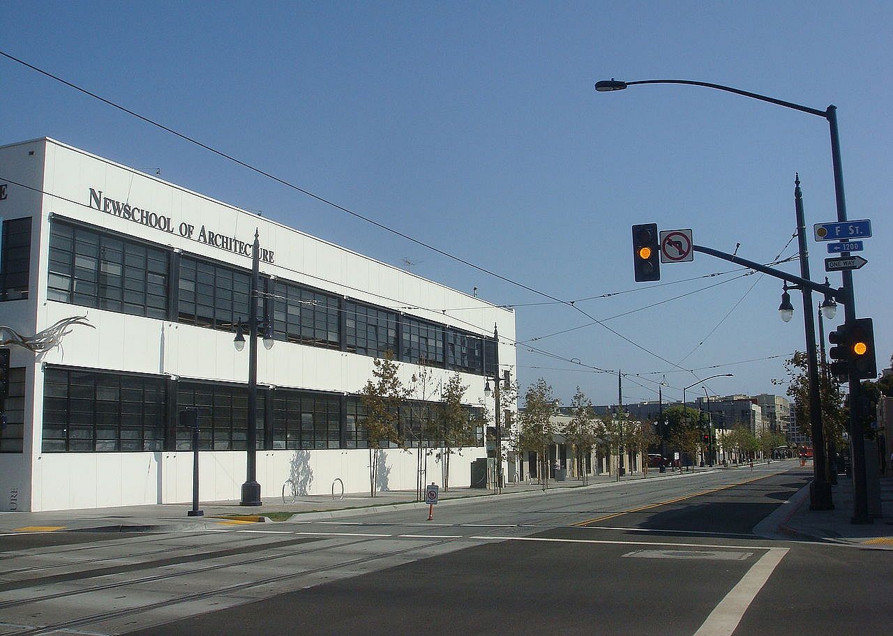 A white building with dark windows and a sign for Newschool of Architecture.