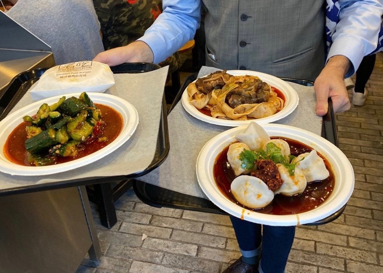 A waiter holding a tray of Chinese dishes.