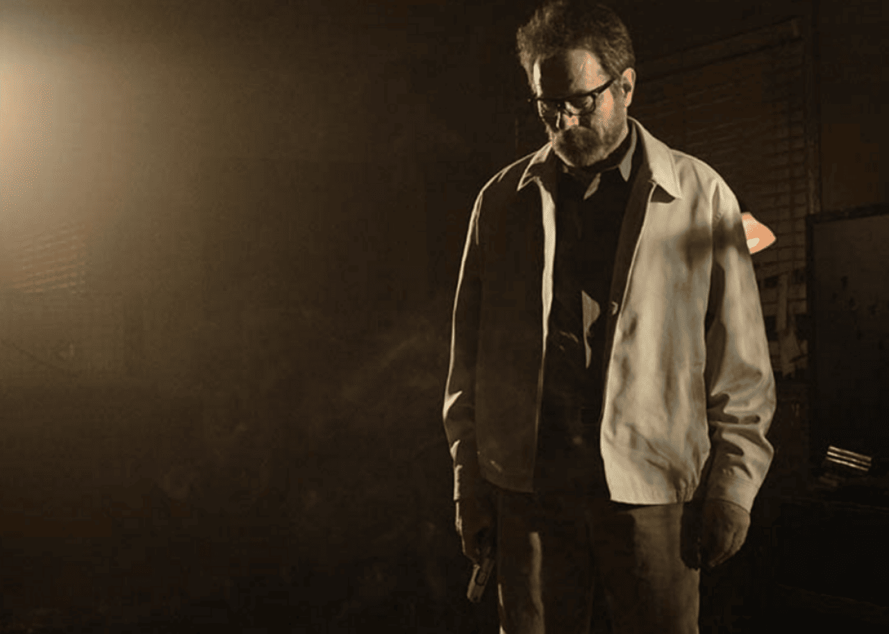 Bryan Cranston, looking disheveled, holding a gun.