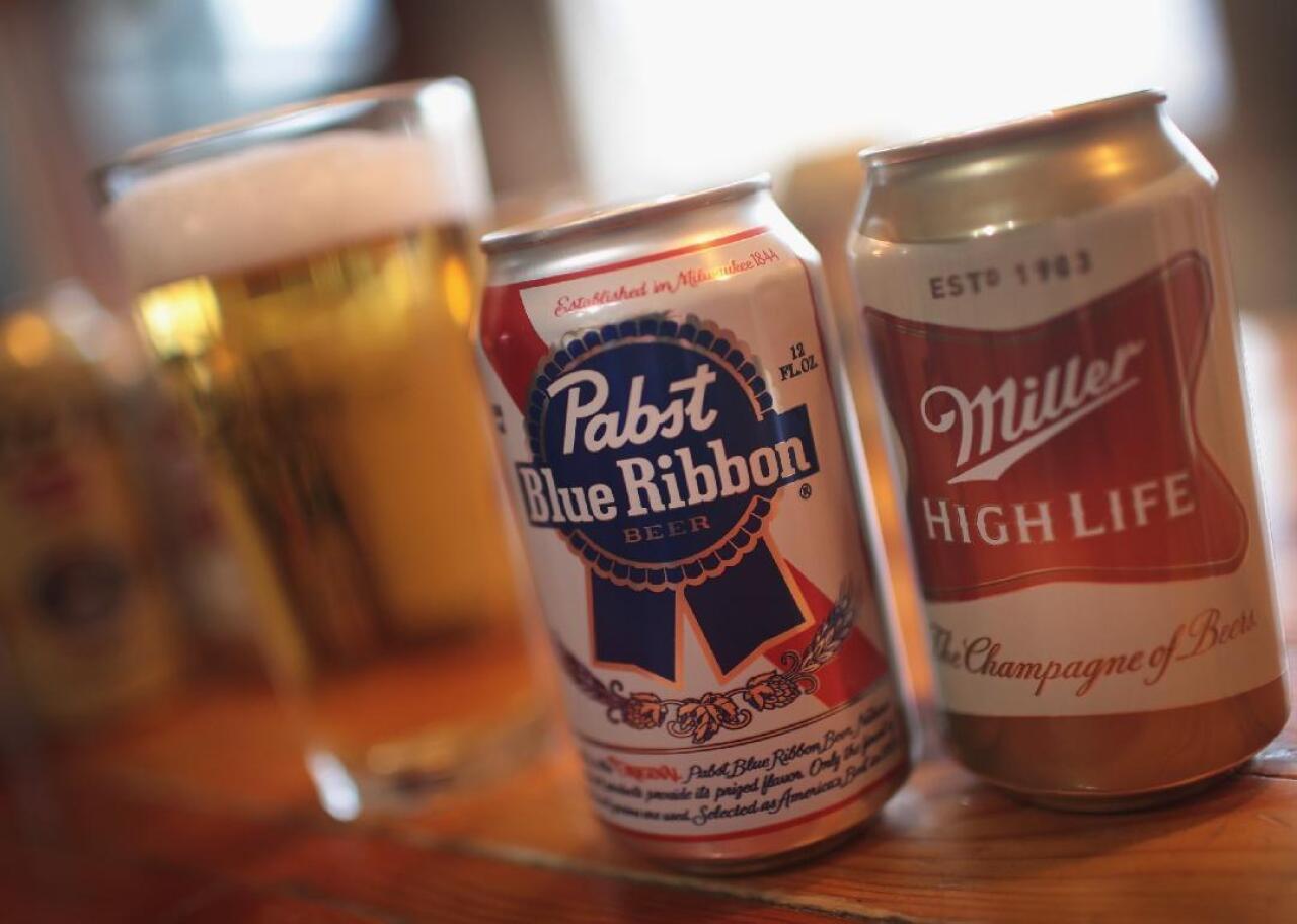 Cans of Pabst Blue Ribbon and Miller High Life sit on a bar.
