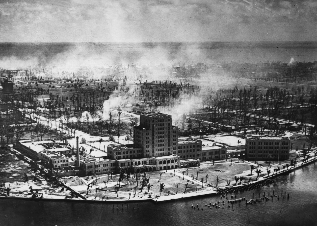 An aerial view of smoke plumes emerging from a city near the coast.