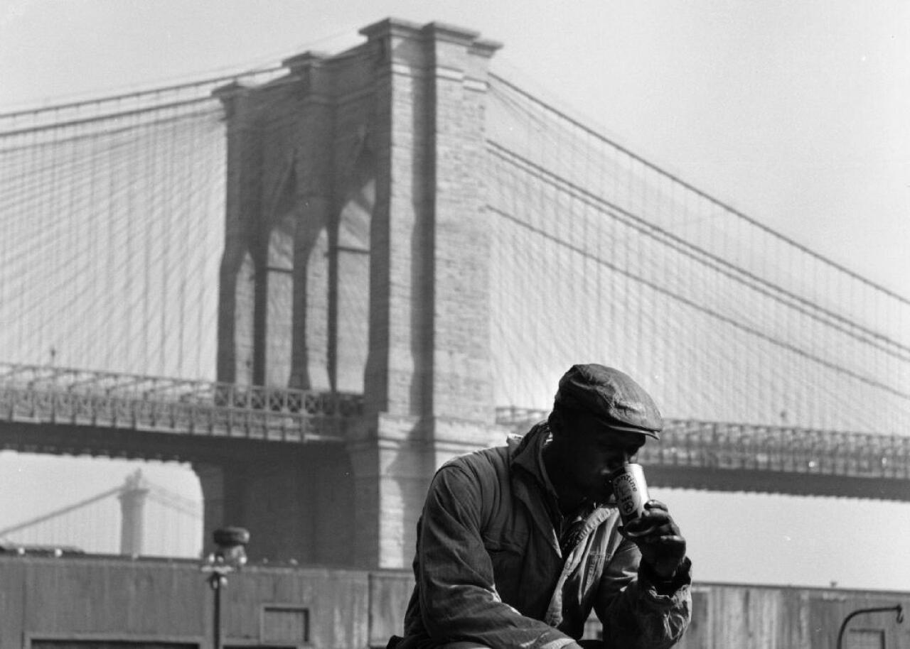 A man enjoys a Ballantine beer near the Brooklyn Bridge.