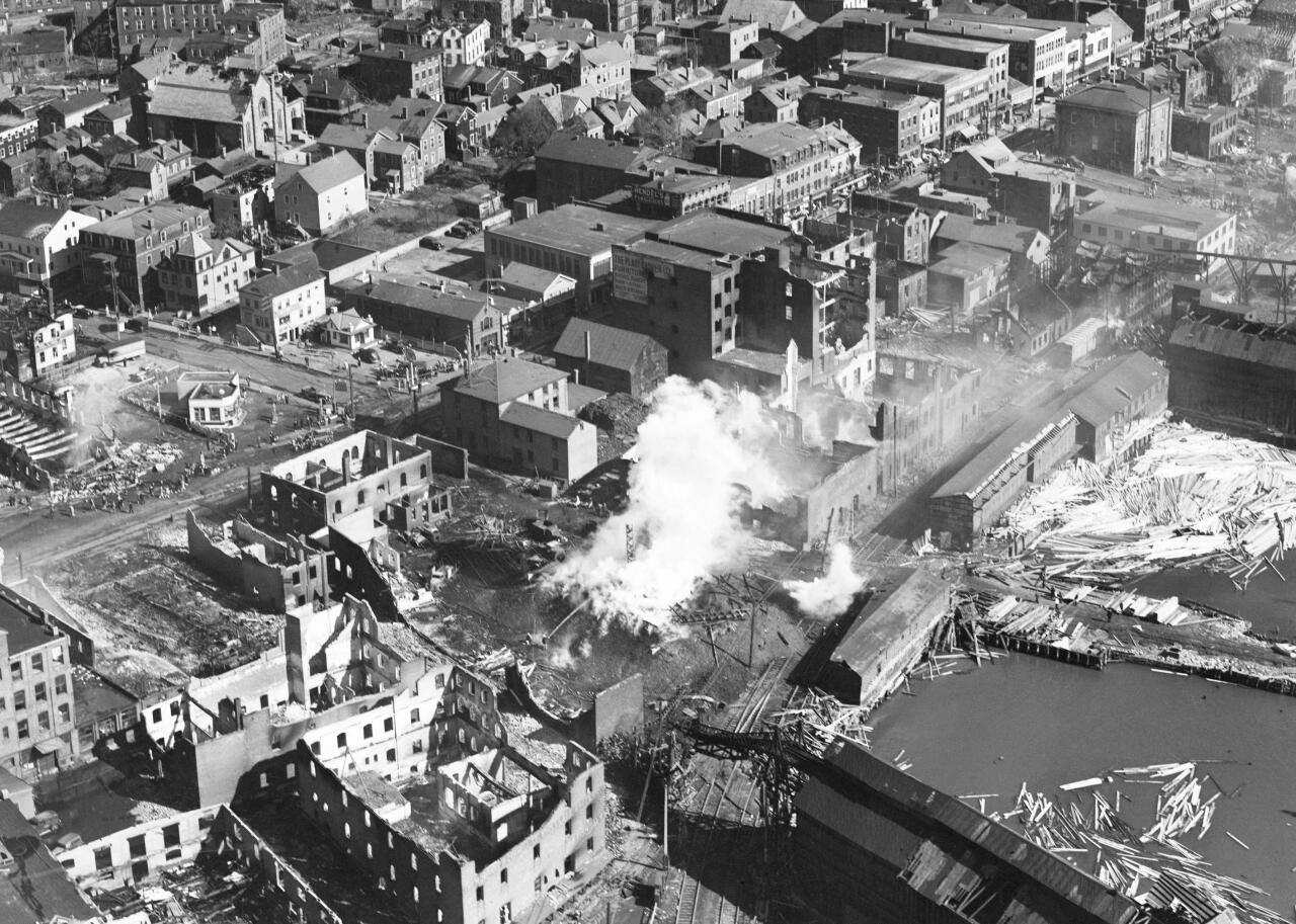 An aerial view of waves crashing against destroyed buildings. 
