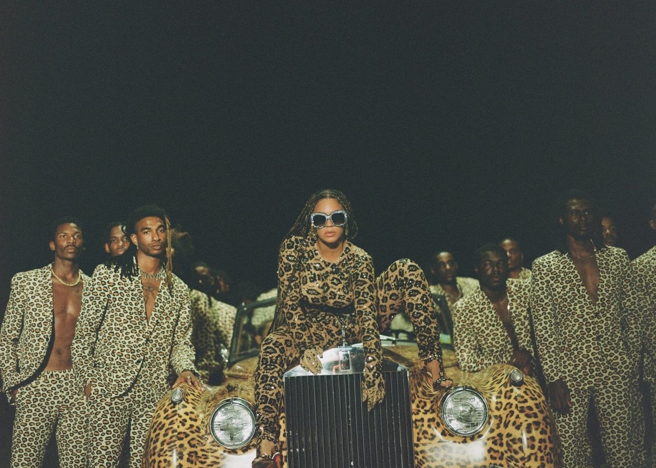 Beyonce and a group of men in animal print on a car wrapped in animal print.