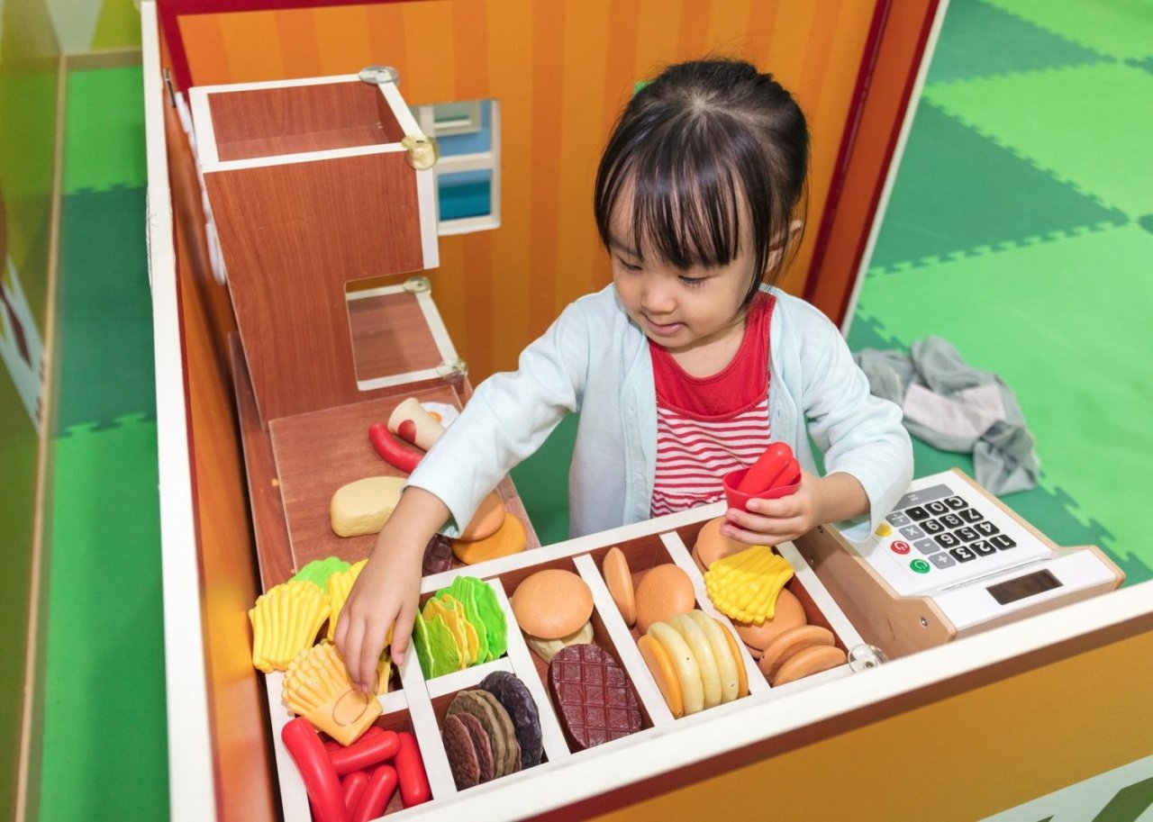 A little girl playing with food toys.