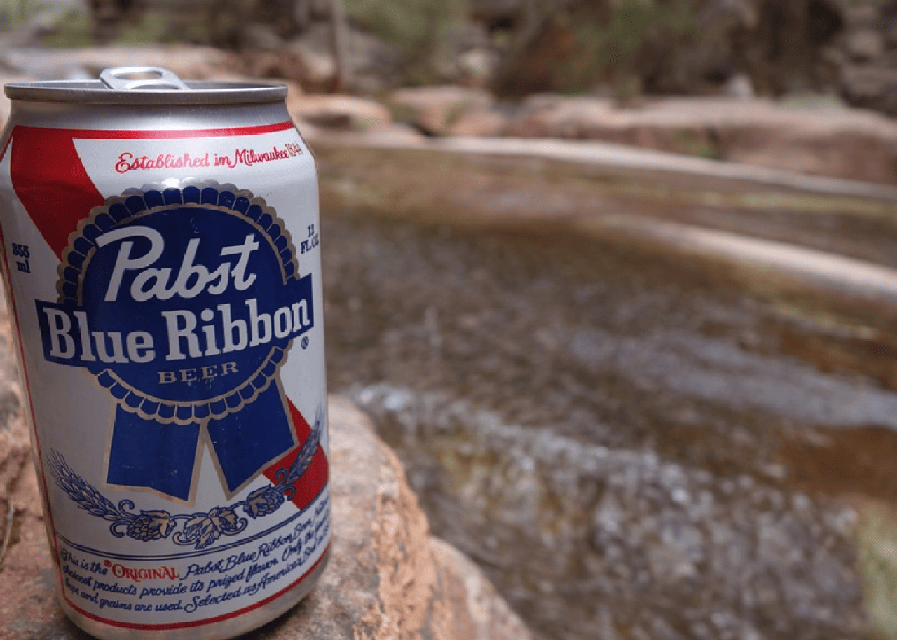A can of Pabst Blue Ribbon Beer sits on a rock.