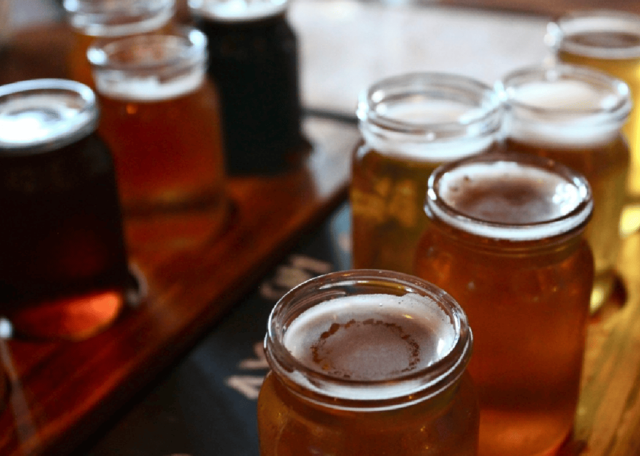 Several beers served in glass jars. 